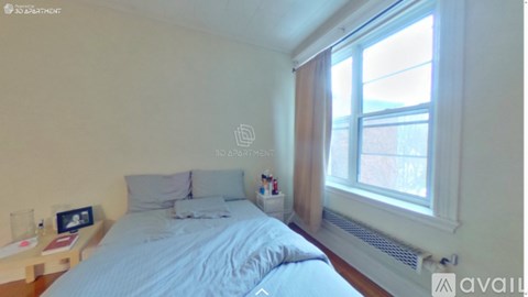 A bedroom with a bed, nightstand, and window.