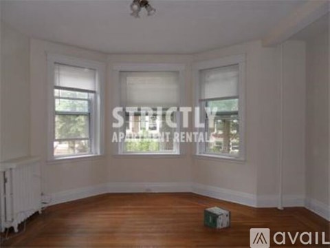 A room with a box on the floor and a window with blinds.