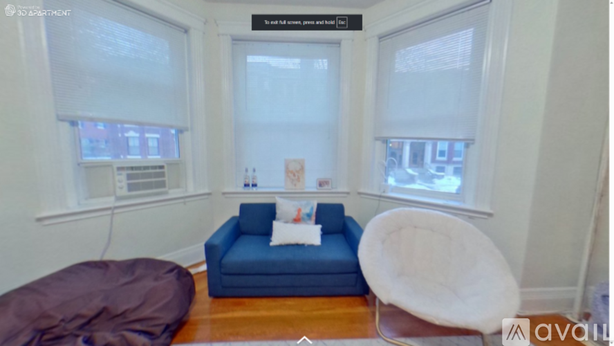 A living room with a blue couch and a white chair.