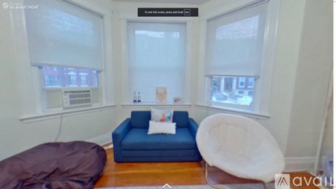 A living room with a blue couch and a white chair.