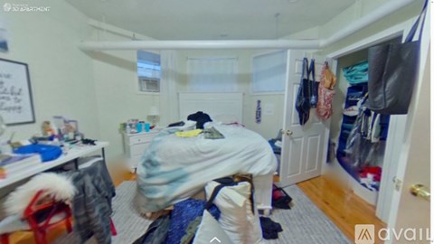 A bedroom with a bed in the middle and a closet full of clothes.