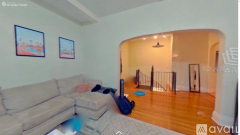 A living room with a couch, a backpack, and two pictures on the wall.