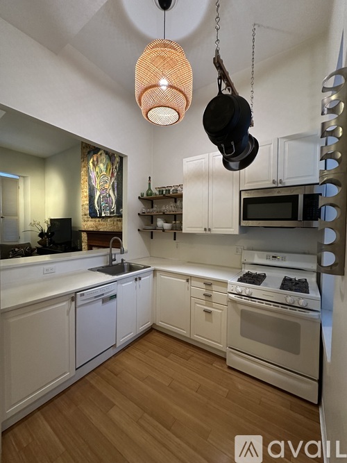 A kitchen with white cabinets and a wooden floor.