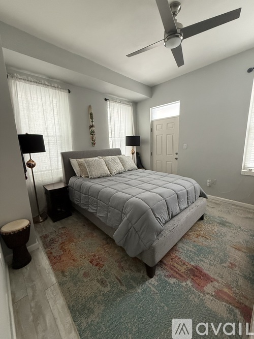 A bedroom with a bed, a fan, and a rug.