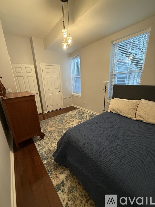A bedroom with a bed, a dresser, and a window with blinds.