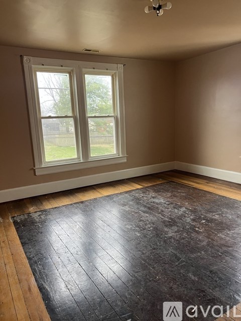 A room with a large window and a wooden floor.