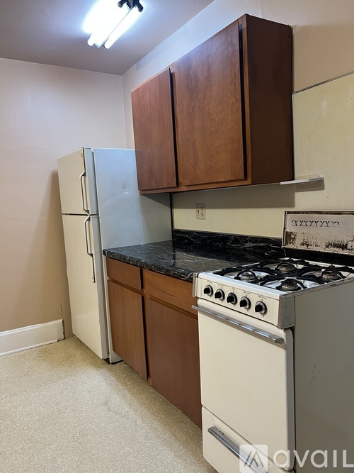 A kitchen with a white fridge, a black stove, and brown cabinets.