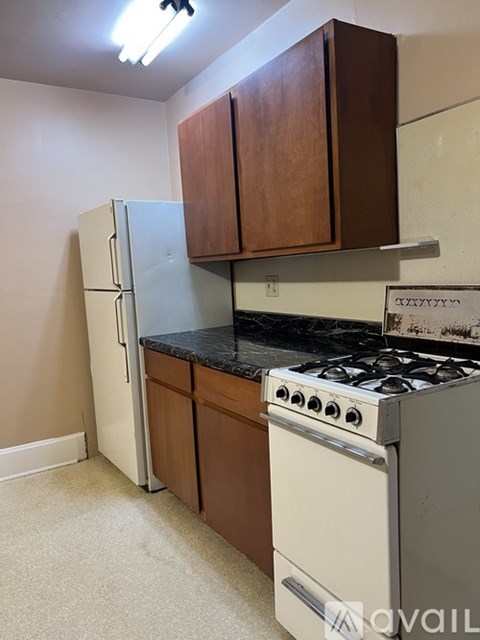 A kitchen with a white fridge, a black stove, and brown cabinets.