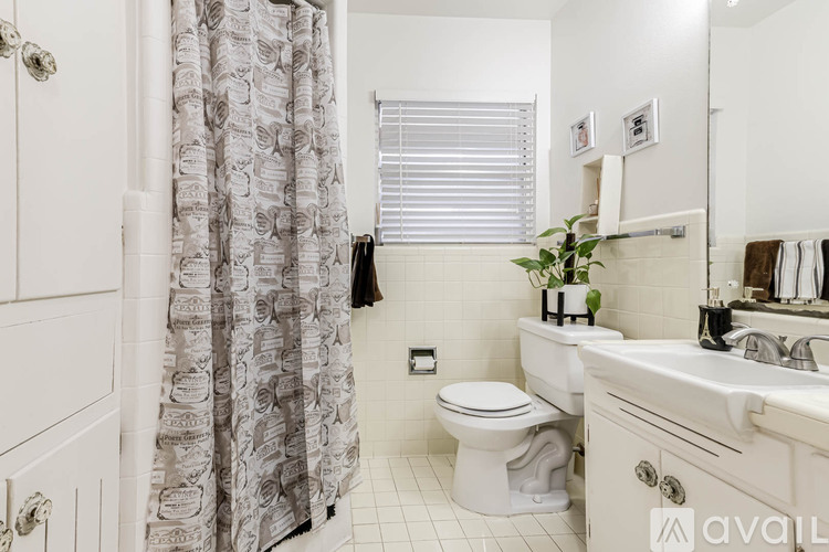 A bathroom with a toilet, sink, and shower curtain.