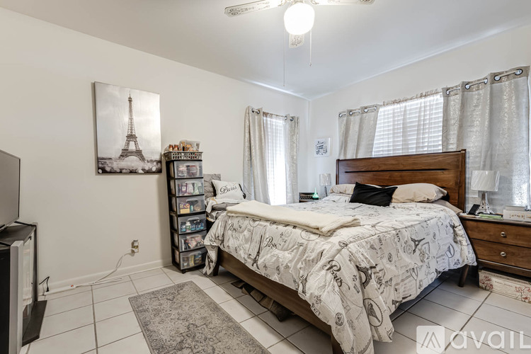 A bedroom with a bed, nightstand, and a picture of the Eiffel Tower on the wall.