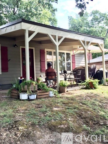 A man is sitting on a chair on a porch with a planter box in front of him.