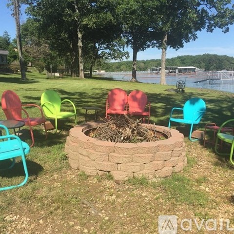 A fire pit surrounded by colorful chairs in a grassy area.