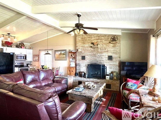 A living room with a brown leather couch and a stone fireplace.