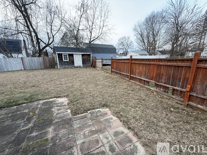 A backyard with a wooden fence and a brick patio.