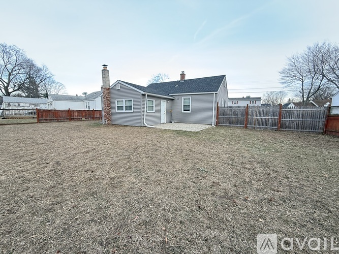 A backyard with a house and a fence.