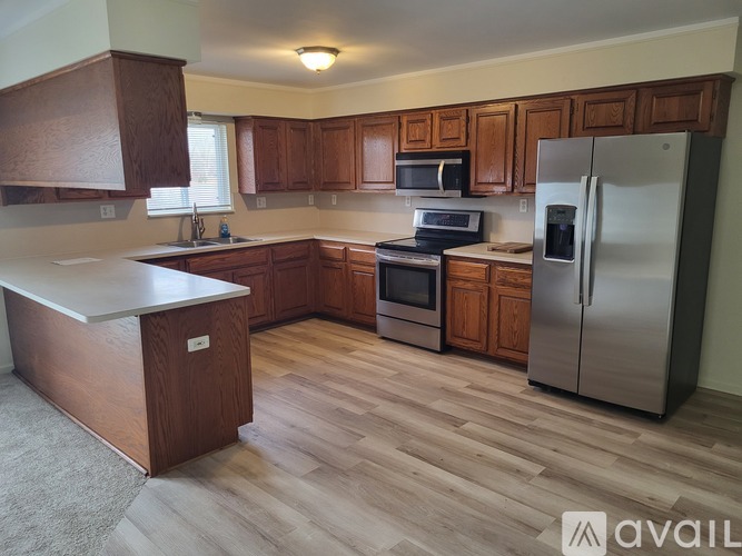 A kitchen with wooden cabinets and a stainless steel refrigerator.