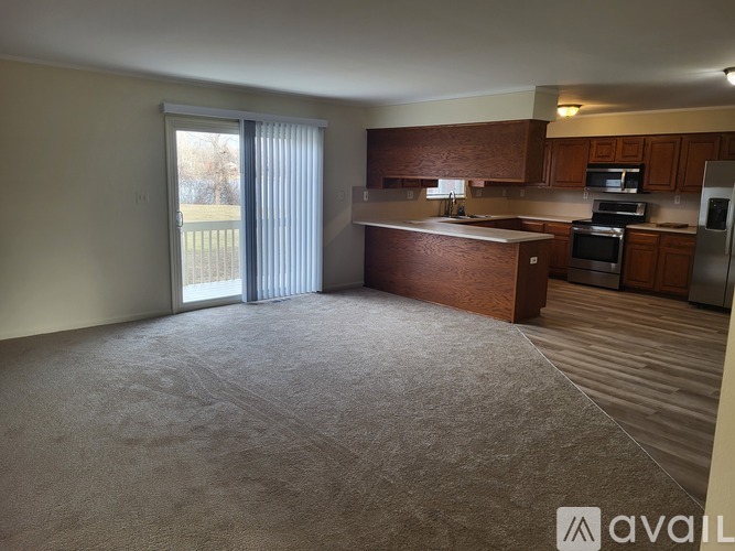 A carpeted living room with a sliding glass door leading to a backyard.