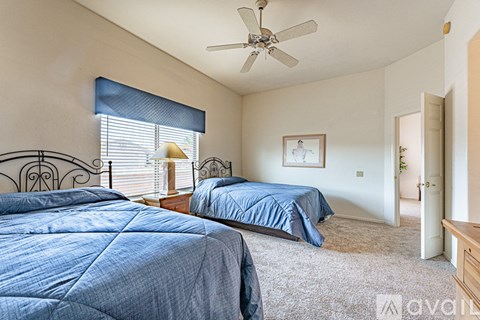 A bedroom with two beds and a ceiling fan.