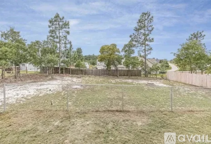 A fenced yard with trees and a clear sky.
