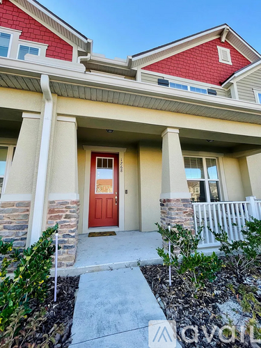 A house with a red door and a porch with white railings.