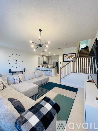A living room with a checkered couch and a clock on the wall.