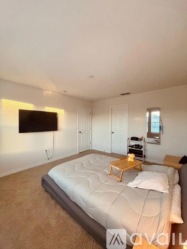 A bedroom with a large bed and a flat screen TV mounted on the wall.