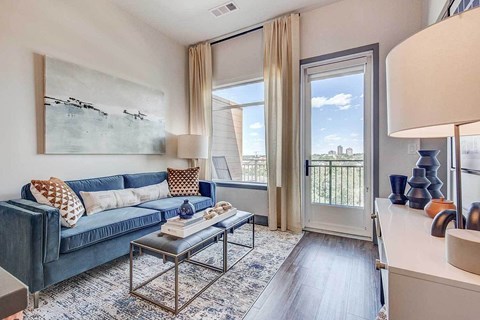 A living room with a blue couch and a large window.