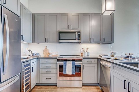 A modern kitchen with a stainless steel refrigerator and a microwave above the oven.