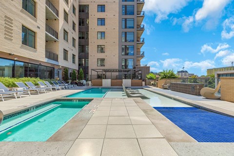 A large swimming pool in front of a building with a sunny day.