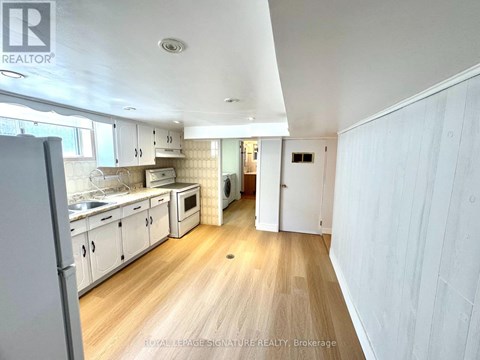 A kitchen with white cabinets and a wooden floor.
