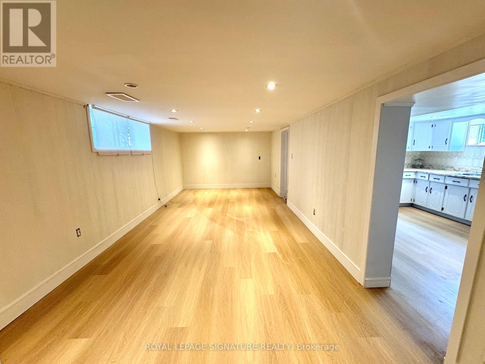 A spacious room with wooden flooring and white walls.