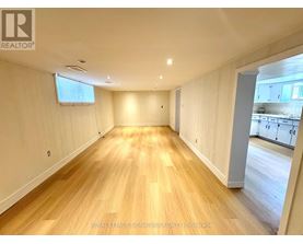 A spacious room with wooden flooring and white walls.