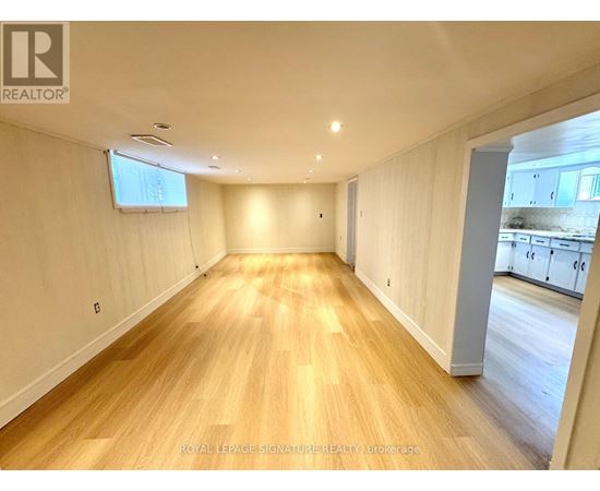 A spacious room with wooden flooring and white walls.