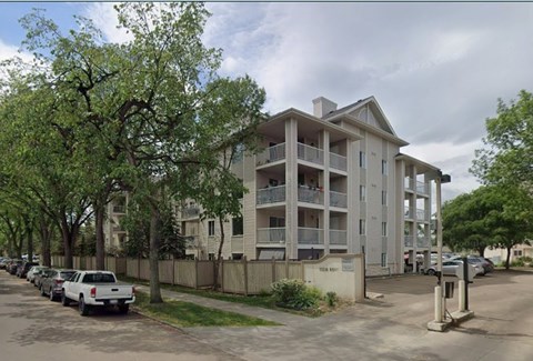 Apartment building with cars parked in front.