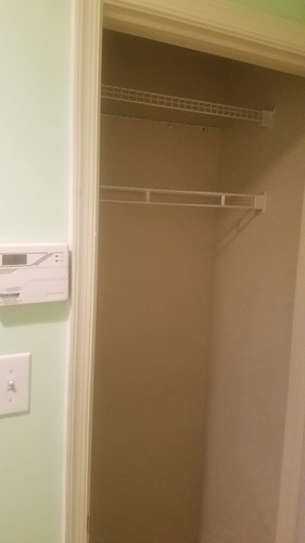 A white shelf is mounted on a green wall.