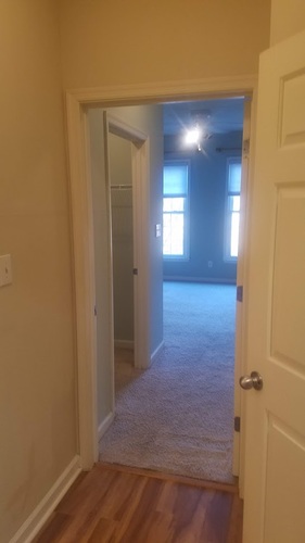 A hallway with a carpeted floor and a door on the right.
