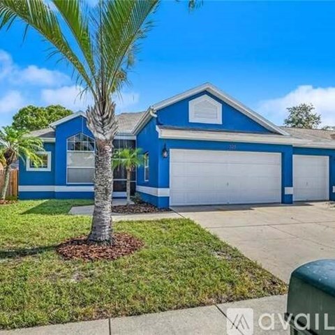 A blue house with a white garage door and a palm tree in front.