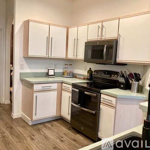 A kitchen with white cabinets and a black microwave.