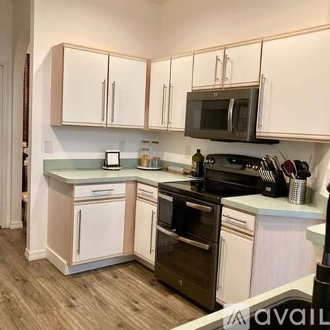 A kitchen with white cabinets and a black microwave.