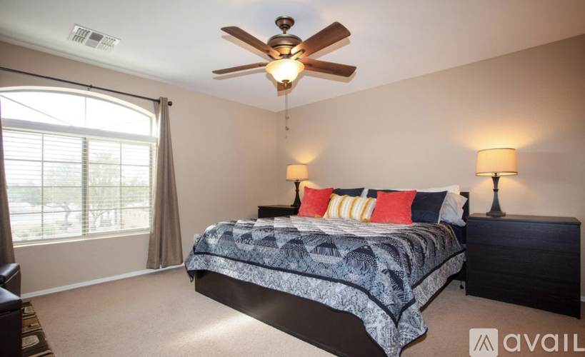 A bedroom with a large bed and a ceiling fan.