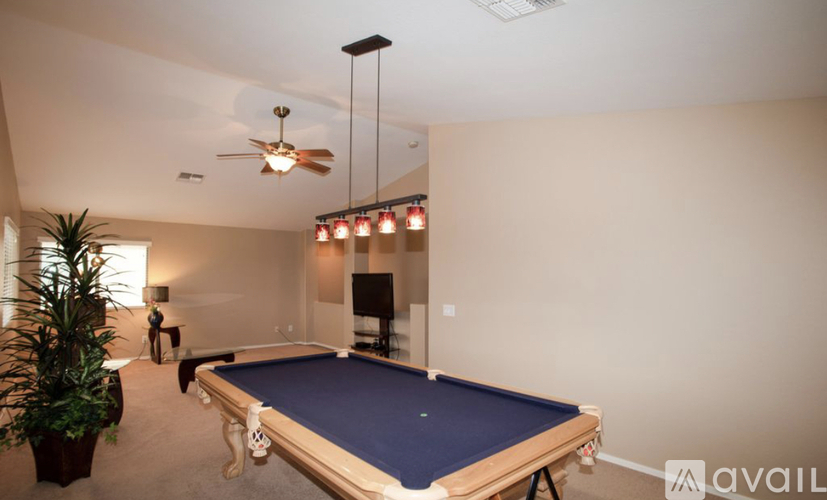 A pool table in a room with a ceiling fan and lights.