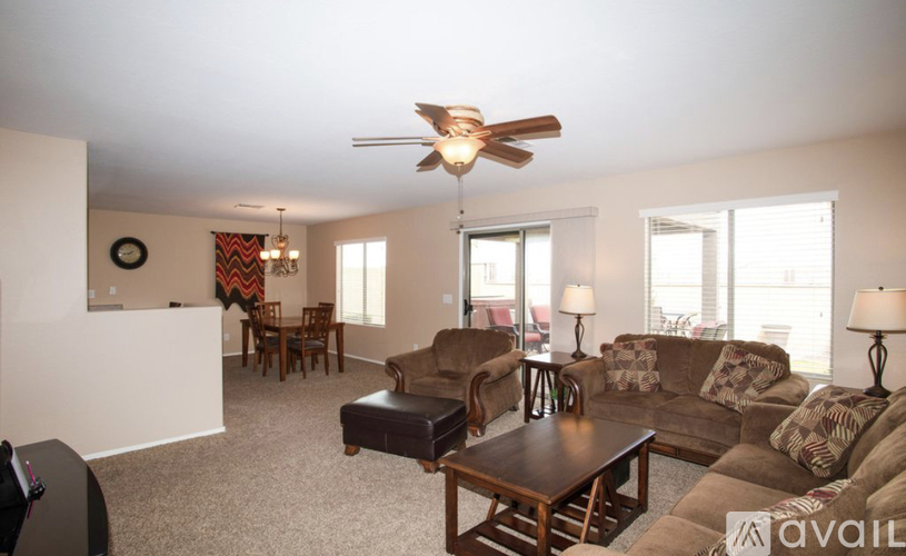 A living room with a brown couch and a ceiling fan.