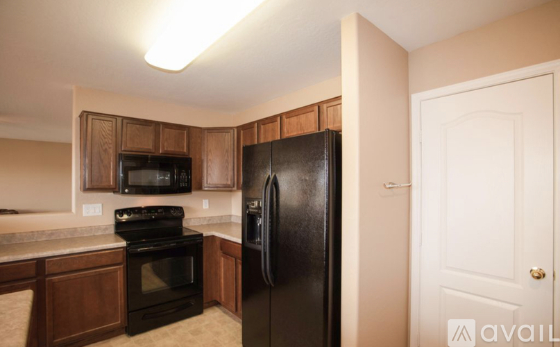 A kitchen with a black refrigerator and wooden cabinets.