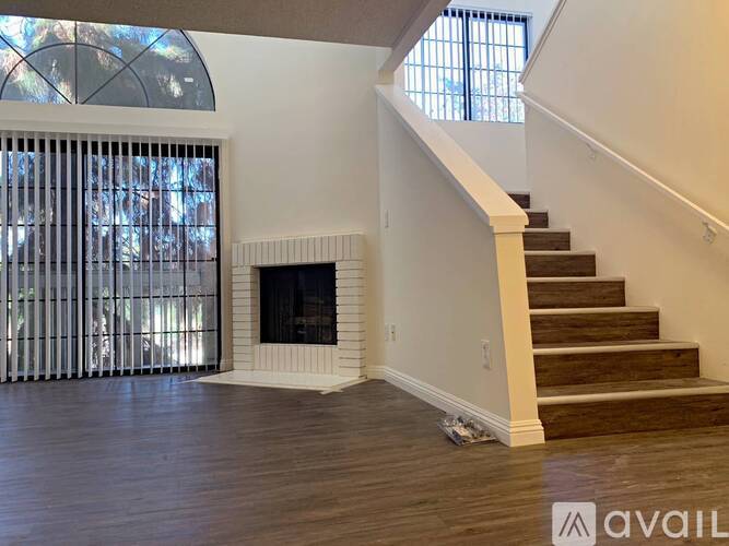 A living room with a fireplace and a staircase.