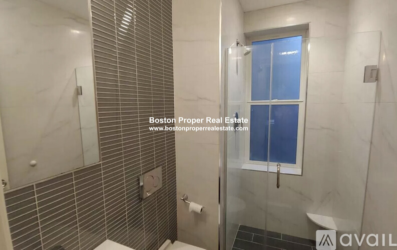 A bathroom with a glass shower door and a toilet.