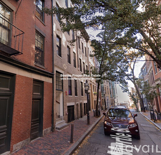 A car is parked on the street in front of a brick building.