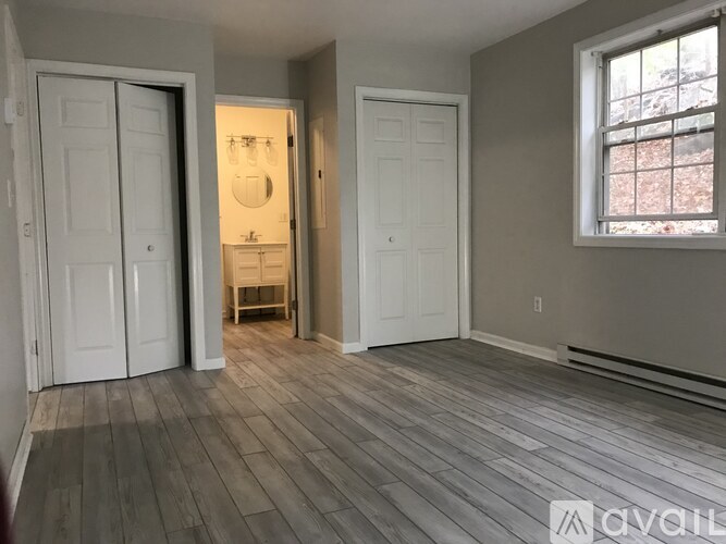 A room with wood flooring and a window on the right side.