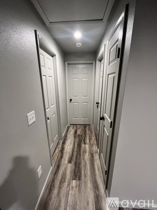 A long hallway with white doors and wood floors.
