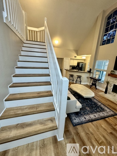 A staircase with wooden steps and white railings leads to a kitchen area.