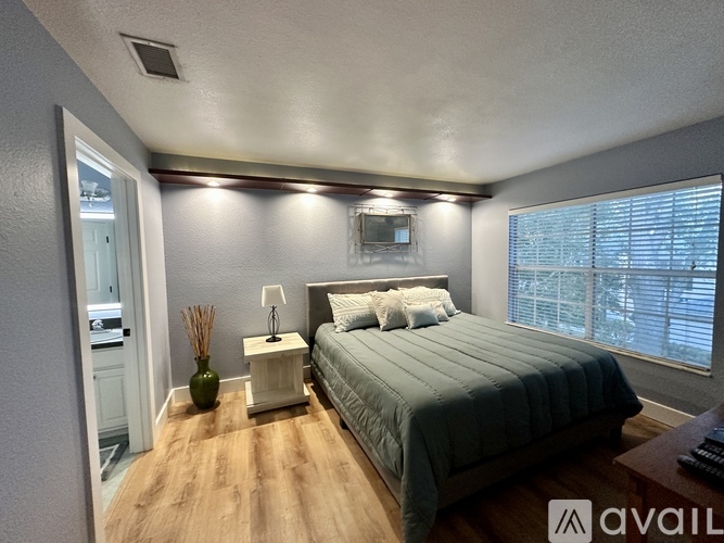 A bedroom with a bed, nightstand, and lamp.